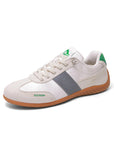 White sports shoes featuring green details on the tongue and heel, a grey side panel with an embossed logo, and a brown outsole, displayed against a white background.