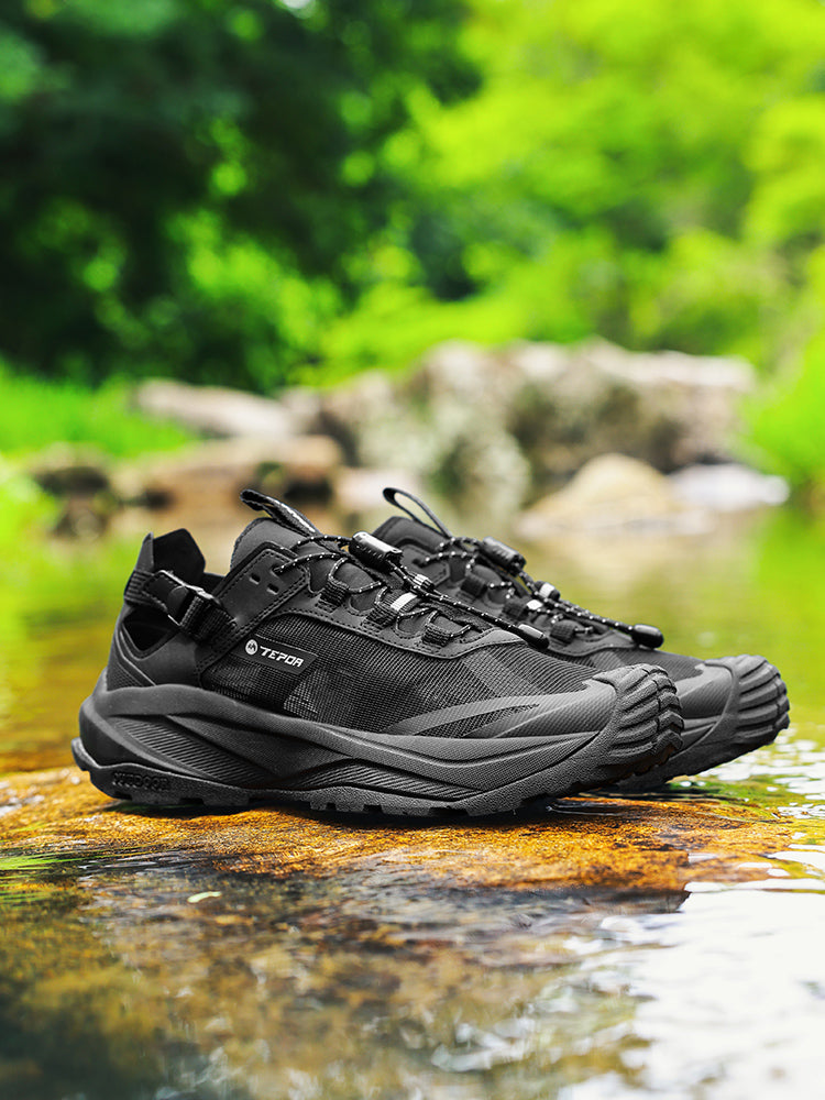 Black ChiYe AquaStride outdoor water shoes placed on a rock by the stream, featuring mesh and leather integration, lightweight MD midsole, anti - slip TPR outsole, and breathable design, suitable for urban and wild areas.