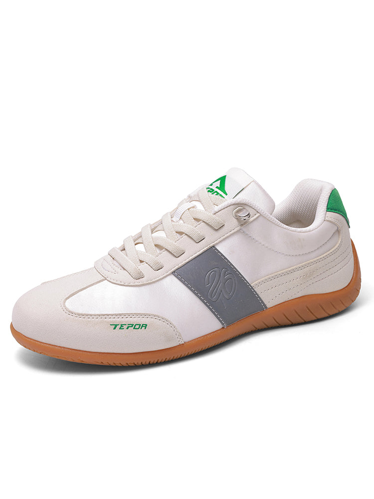 White sports shoes featuring green details on the tongue and heel, a grey side panel with an embossed logo, and a brown outsole, displayed against a white background.